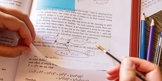 Un étudiant annotant un manuel avec une note Post-it® transparente, surlignant des équations mathématiques
