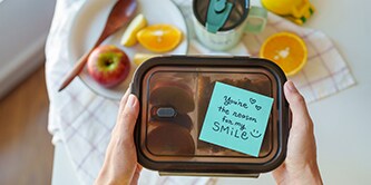Une boîte déjeuner avec un message chaleureux sur une note Post-it® disant "Tu es la raison de mon sourire"
